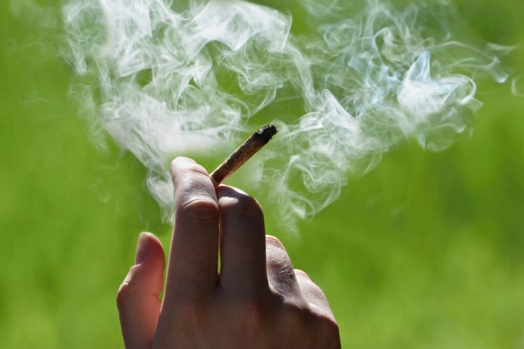 Hand holding lit marijuana joint, indicating that Wisconsin should legalize marijuana.