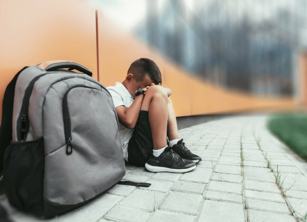 Frightened student next to backpack covering face