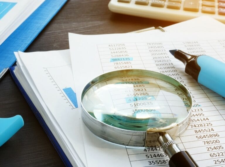 Items for a financial audit: papers, magnifying glass and highligher