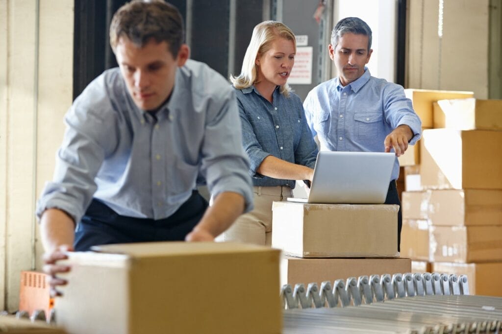 Worker moving box near managers on computer