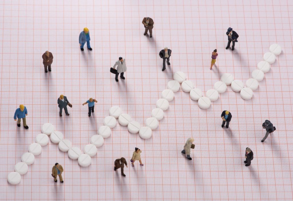 Human figures on a grid with a line graph made of medicinal pills ascending in an upward fashion.