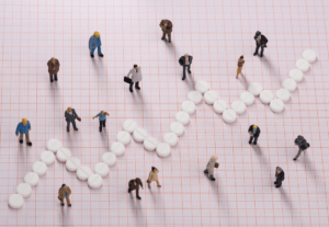 Human figures on a grid with a line graph made of medicinal pills ascending in an upward fashion.