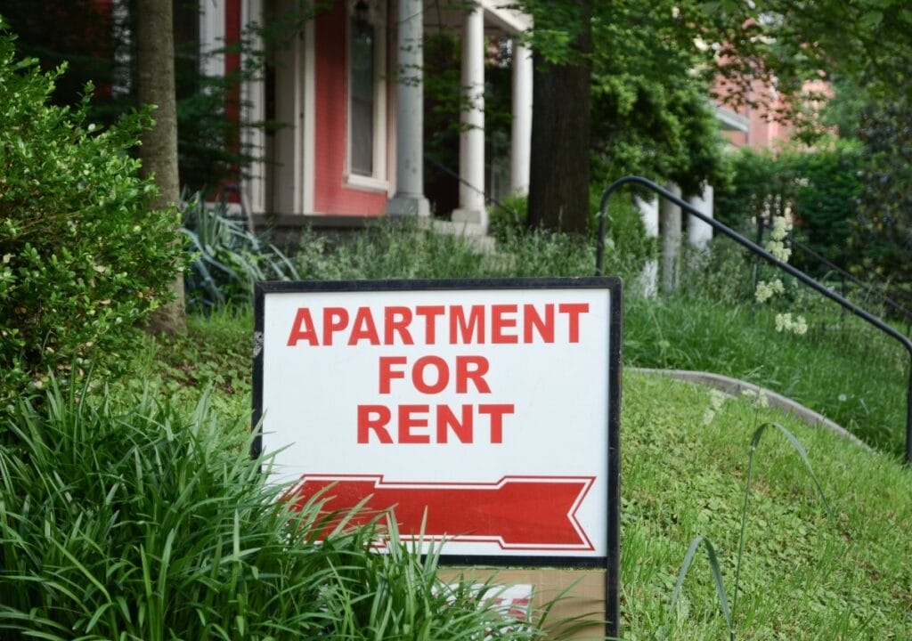 Sign in the front lawn of a rental property reading “Apartment for Rent”