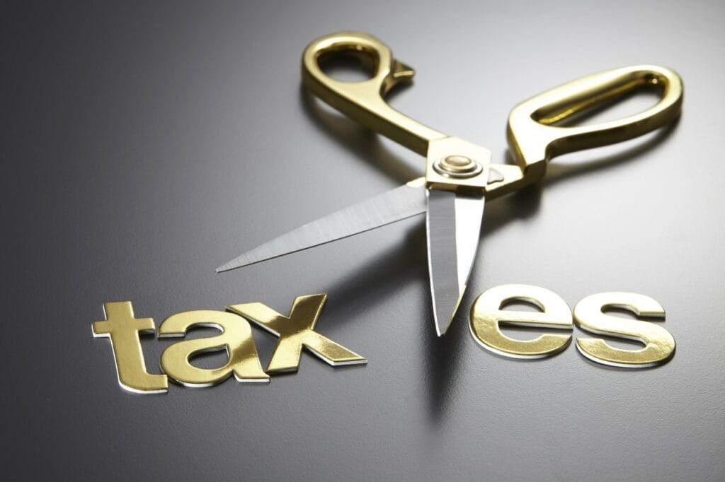 Golden scissors cutting through the word taxes