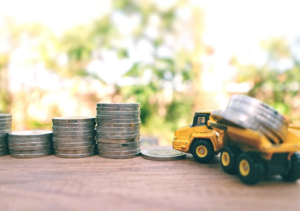 Miniature construction vehicles set among stacks of U.S. coinage.