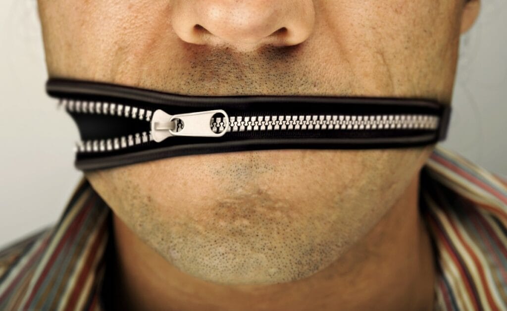 Man whose mouth is represented by a closing zipper, indicative of free speech suppression in the state of Wisconsin