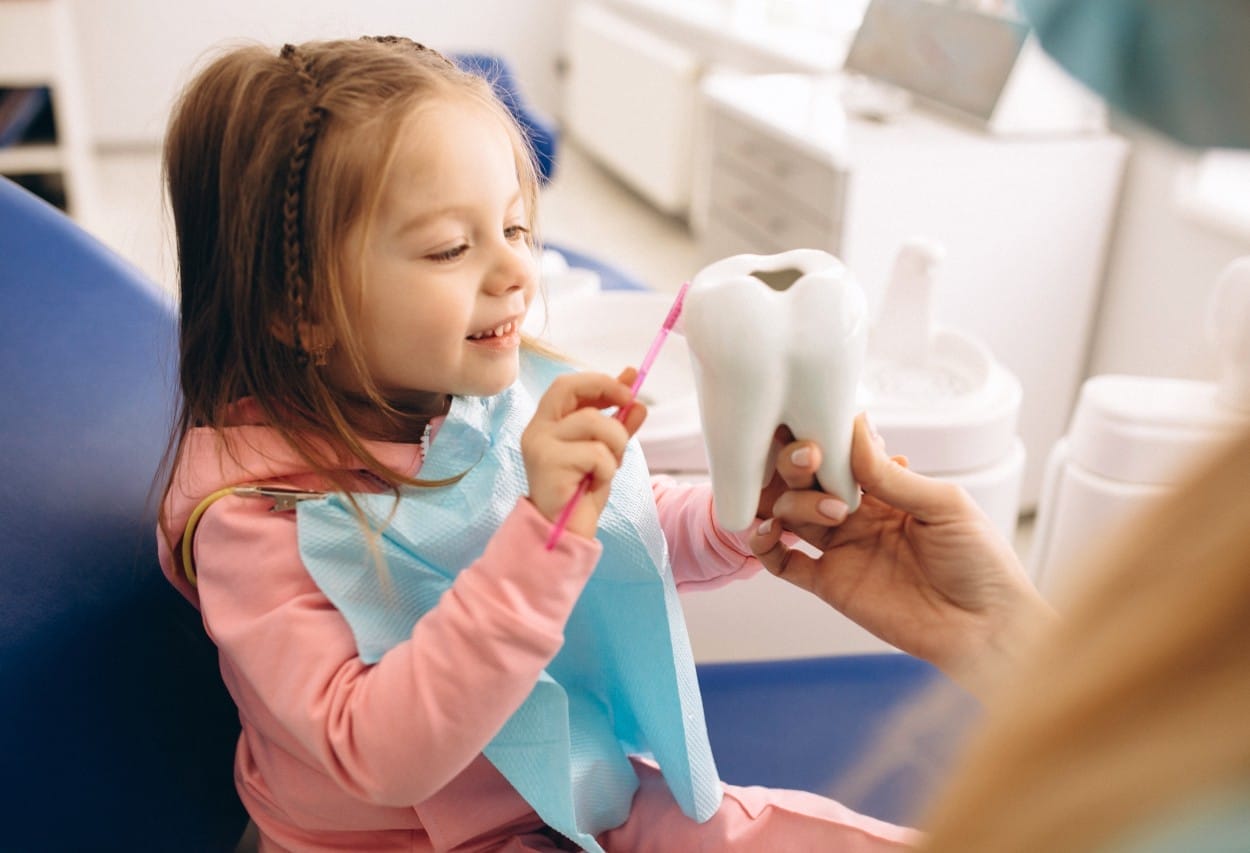Female child being taught how to brush by a Wisconsin dental professional
