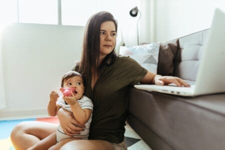 Young mother with an infant working on laptop computer to escape poverty
