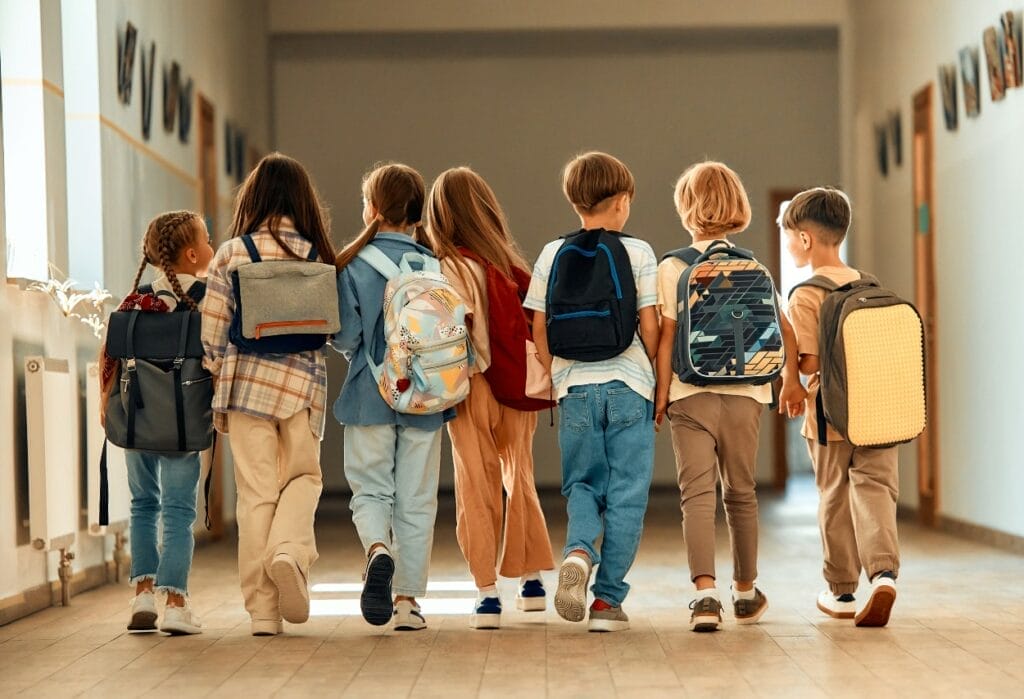 Happy students walking in hall of school