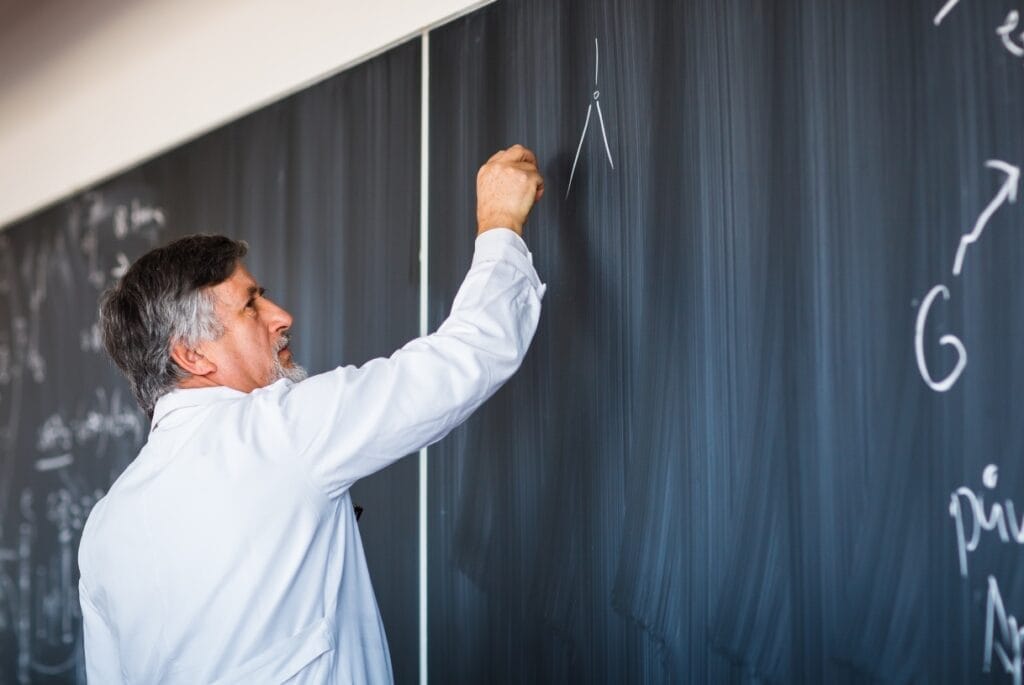 Professor using chalk on chalkboard