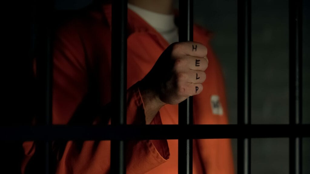 Prisoner with the word help on his hand