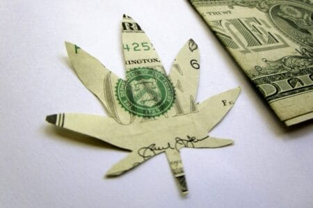 U.S. dollar bill cut into the shape of a cannabis leaf