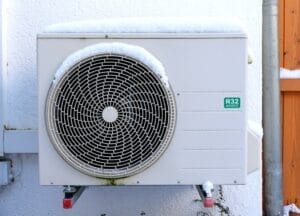 Snow-covered heat pump on frigid Wisconsin home hit by higher long-term energy costs.
