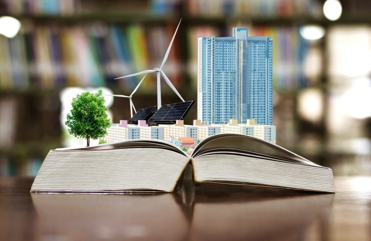 Open book on a table top with windmills and solar panels arising from its pages