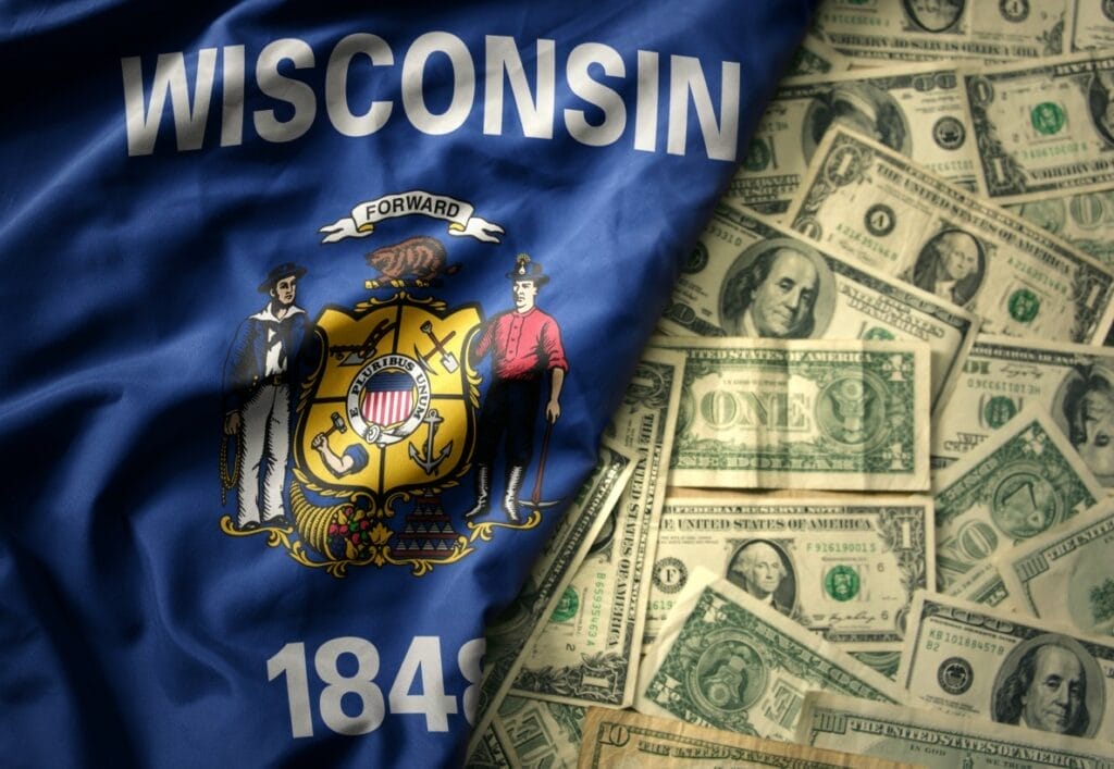 Wisconsin flag set next to a field of U.S. currency bills.