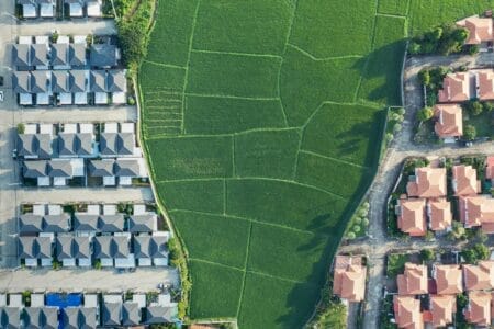 Image depicting two housing developments on each side of green farmland