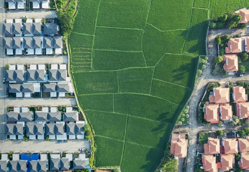 Image depicting two housing developments on each side of green farmland