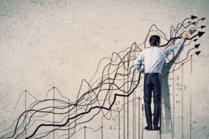 Digital image of a man standing on ladder drawing lines trending in an upward, positive direction