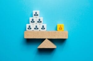 A toy block scale with cubes of lawmakers on one side and a bag of money on the other